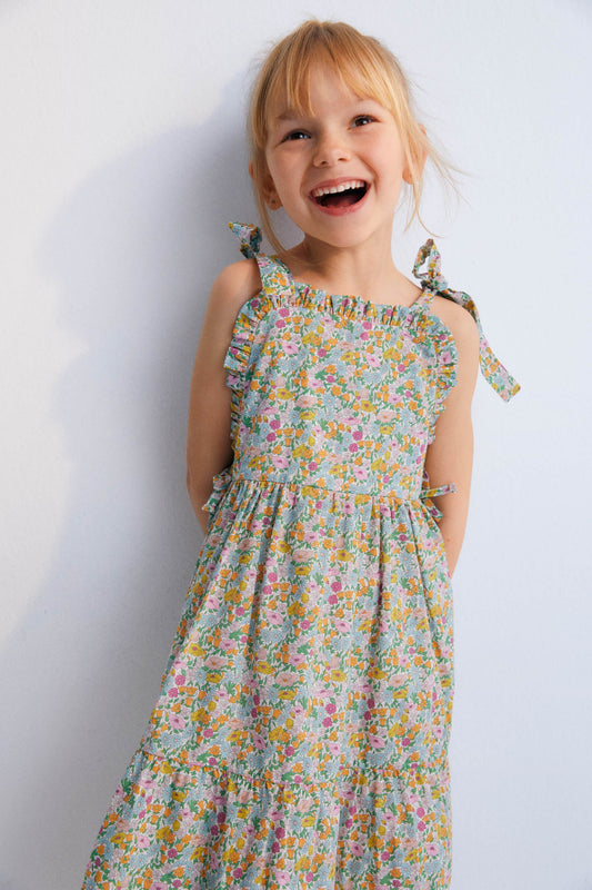 Andreas Dress in Liberty fabric, with front ruffles and a cut to create volume in the ruffle, with bow details on the sides and shoulder straps. Spring Summer Collection. The New Scoiety. 