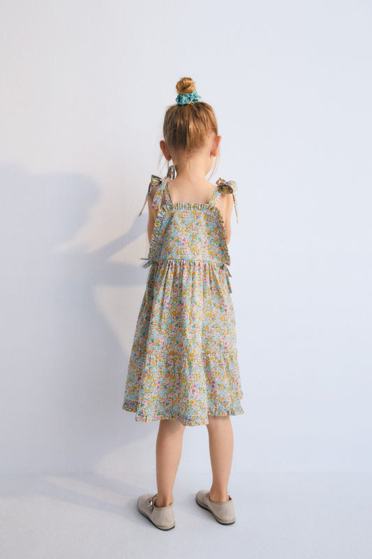 Andreas Dress in Liberty fabric, with front ruffles and a cut to create volume in the ruffle, with bow details on the sides and shoulder straps. Spring Summer Collection. The New Scoiety. 