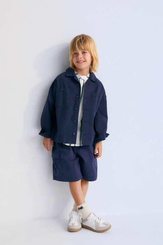 Artemis Bermuda in 100% cotton twill, garment-dyed in navy color.  With an elastic waistband and adjustable drawstring  and cargo pockets on the sides.