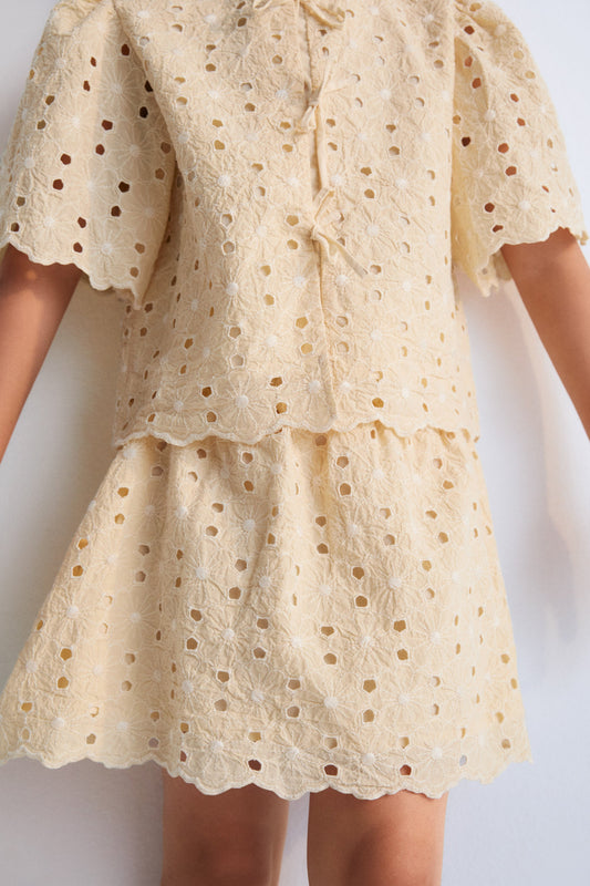 Creta Blouse in embroidered blend cotton fabric in macadamia color, featuring gathered sleeves, a high neckline, and central bow closure. New Collection Kids