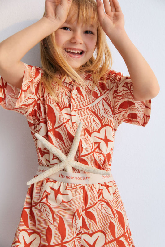 Filotis Short in 100% cotton fabric with our chili mountain rose print, featuring an elastic waistband in chili with macadamia-colored letters. Spring Summer Collection. The New Society. 