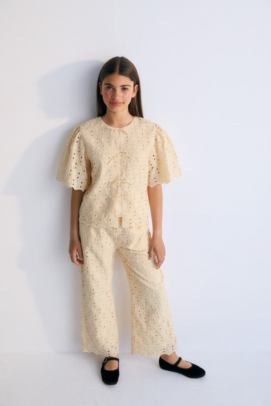 Creta Blouse in embroidered blend cotton fabric in macadamia color, featuring gathered sleeves, a high neckline, and central bow closure. New Collection Kids